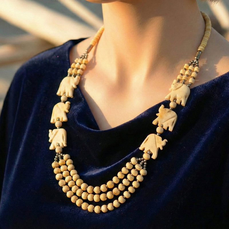 Handcrafted beige beaded necklace with carved elephant pendants and brass accents
