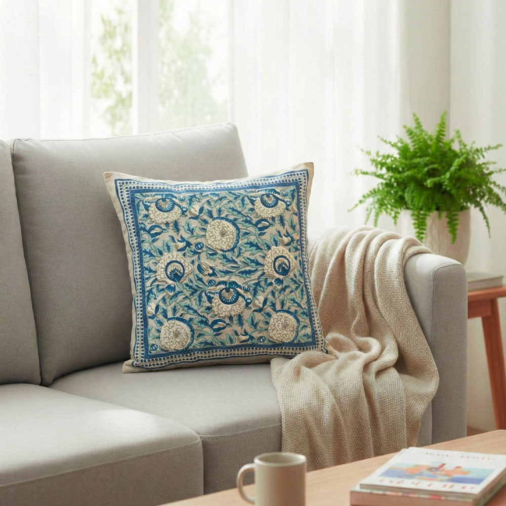 Light gray fabric sofa with beige pillow featuring navy blue abstract design and gray knitted throw blanket