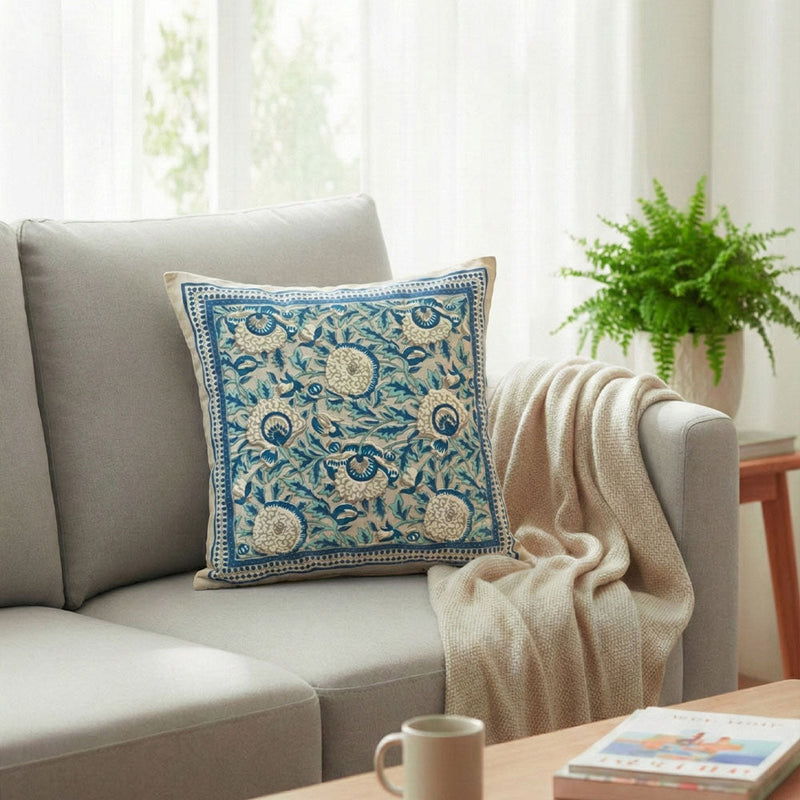 Light gray fabric sofa with beige pillow featuring navy blue abstract design and gray knitted throw blanket