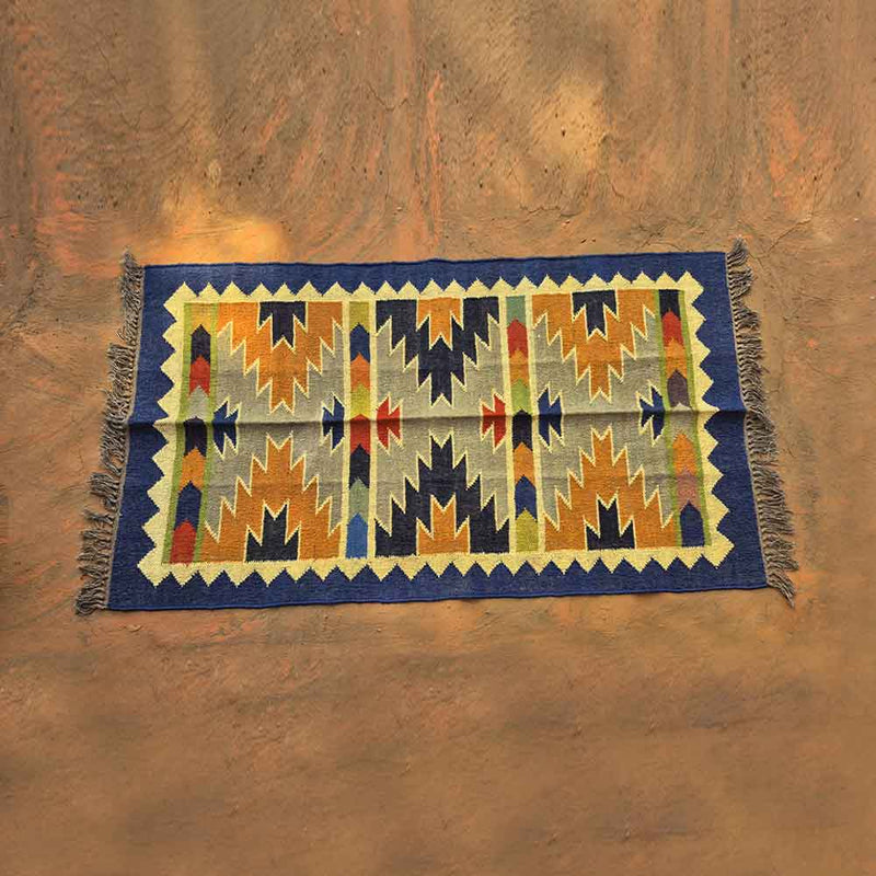 Geometric patterned woven rug with blue border and multicolor zigzag designs and tassels