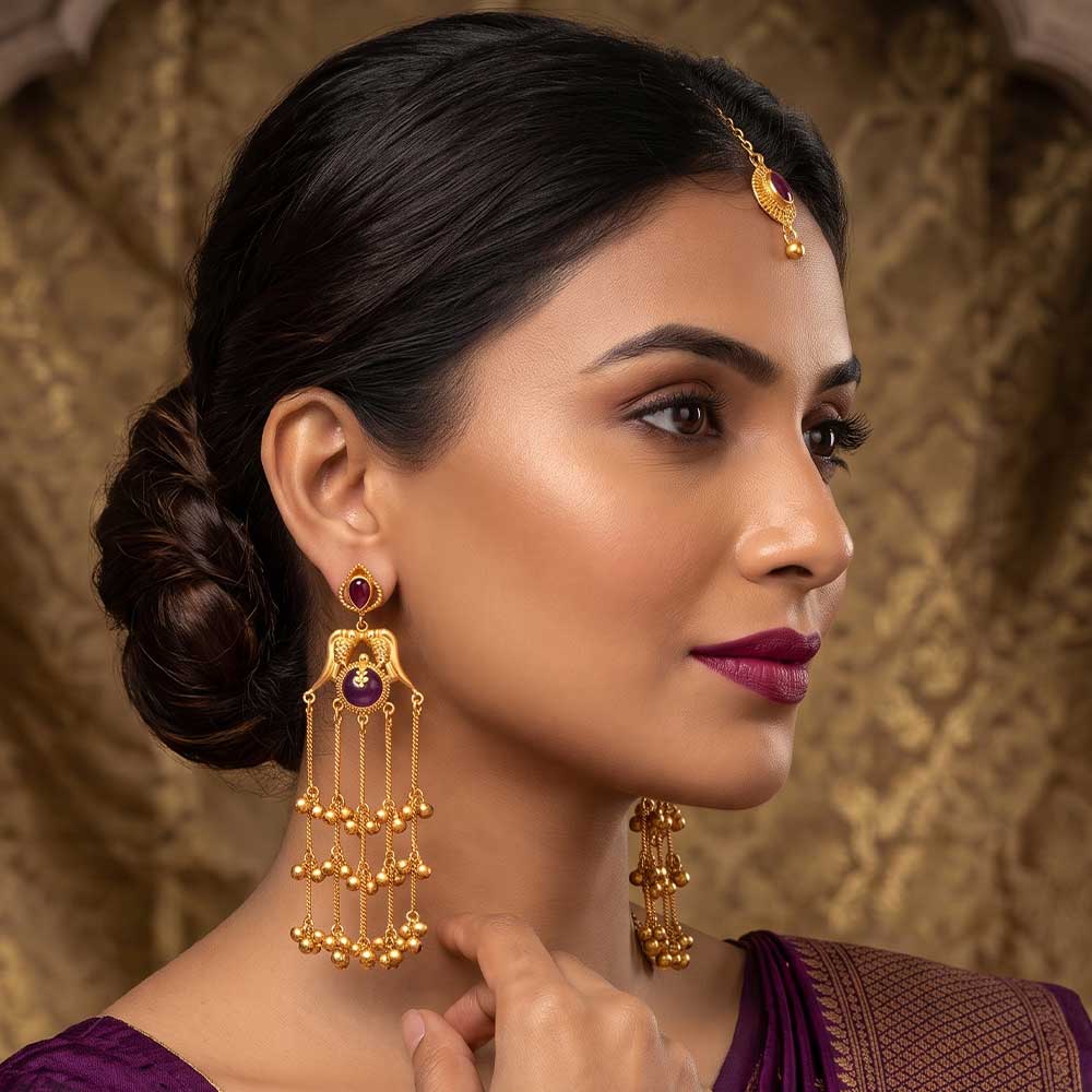 Close-up detail of the peacock motif and purple stone on the gold plated jhumka earring
