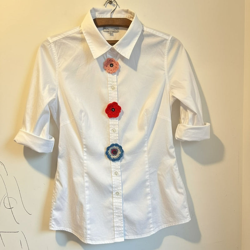 Light grey crocheted flower applique with six petals on white background