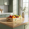 Fruit basket on a kitchen counter with green cabinets and a window in the background