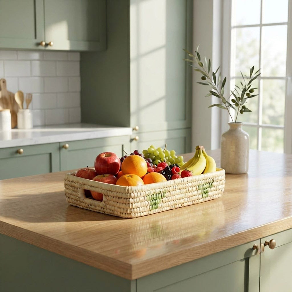 Fruit basket on a kitchen counter with green cabinets and a window in the background