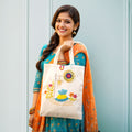 Woman holding a tote bag with decorative design against a light blue background