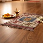 Decorative rug with intricate patterns on a wooden floor, accompanied by a small plate of snacks and a lit lamp.