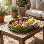 Breakfast tray with croissants, coffee, and fruit on a wooden table outdoors.