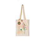 Beige canvas tote bag with embroidered brick window, flowers, and hanging ornament detail
