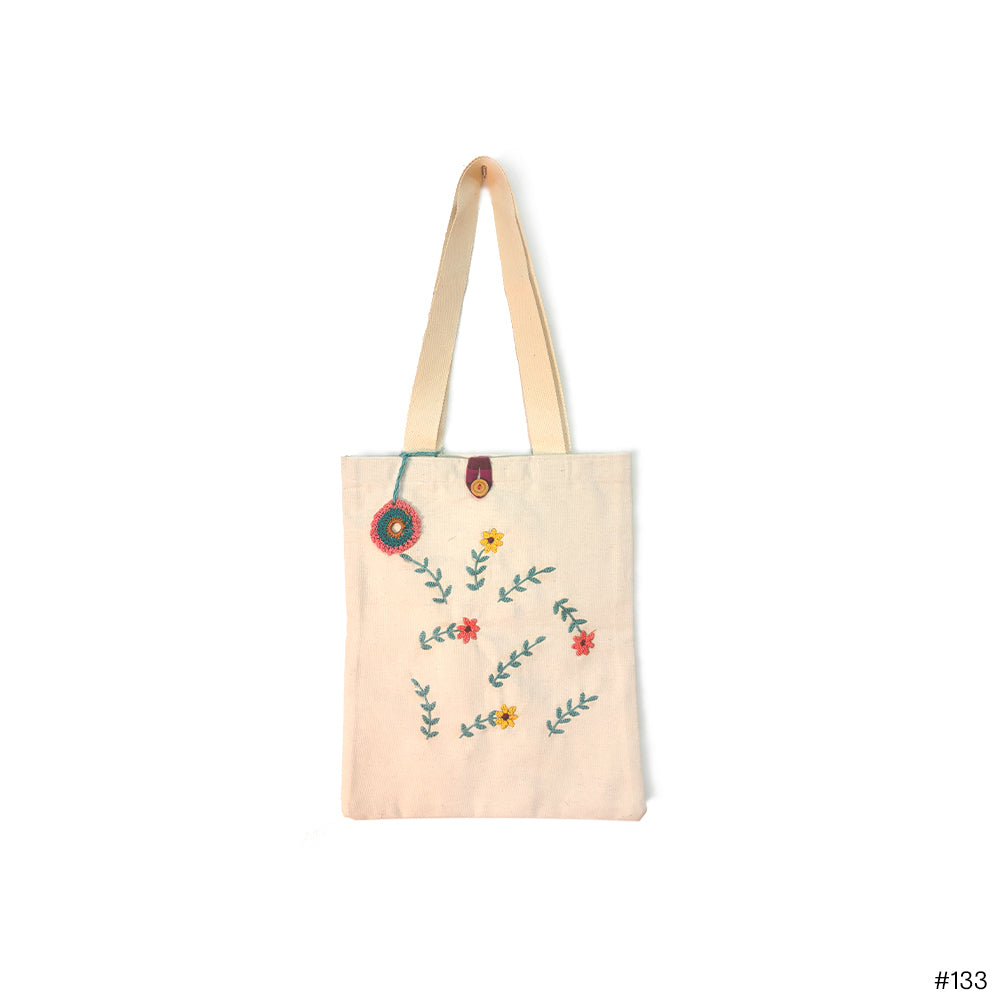 Beige canvas tote bag with embroidered colorful floral design and button closure
