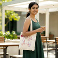 Woman holding a floral tote bag and a cup outdoors