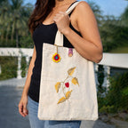 Person holding a tote bag with floral embroidery outdoors
