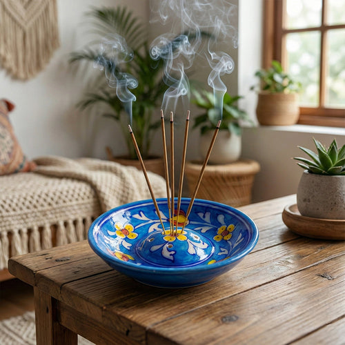 Blue ceramic bowl with incense sticks on a wooden table in a home setting