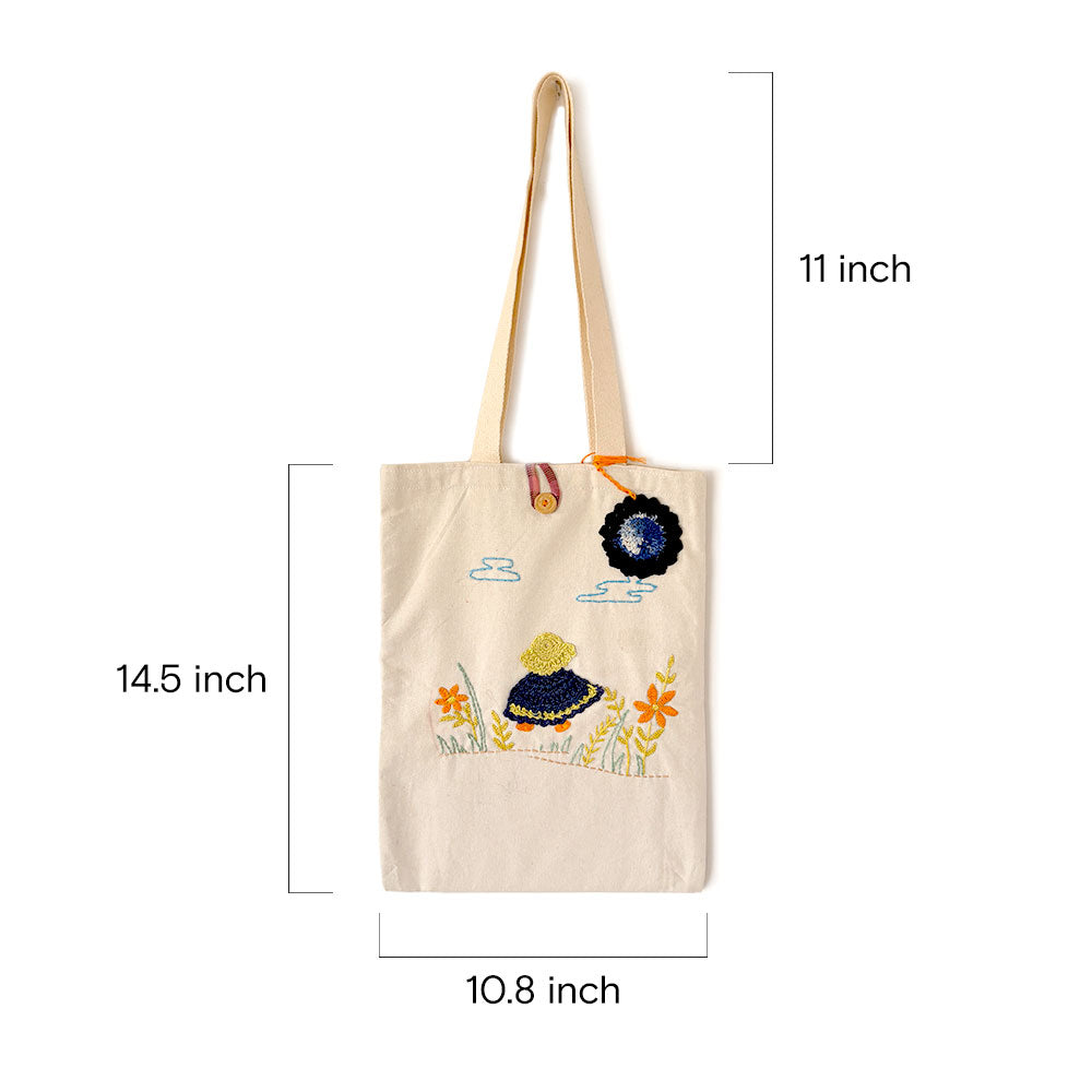 Beige canvas tote bag with embroidered girl and flowers, measuring 14.5x10.8 inches with 11-inch straps