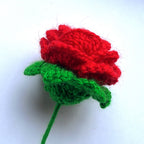 Knitted red rose with green leaves on a white background
