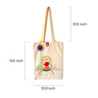 Beige canvas tote bag with embroidered girl under floral arch and measuring dimensions