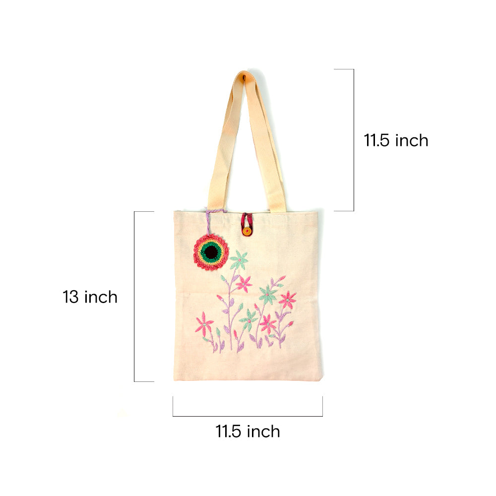 Beige fabric tote bag with pink and green floral embroidery, 11.5x13 inches, shoulder straps