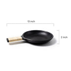 Black frying pan with wooden handle and measurements on a white background