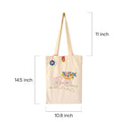 Beige canvas tote bag with embroidered pink bicycle and colorful floral basket, measuring 14.5x10.8 inches