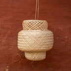Woven rattan pendant light against a red-brown wall