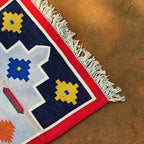 Close-up of a colorful patterned rug with geometric design on a textured surface.
