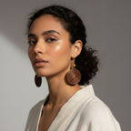 Woman wearing large earrings against a neutral background