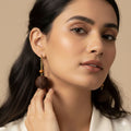 Woman wearing a pair of earrings with a neutral background