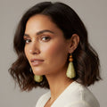 Woman wearing green earrings against a neutral background