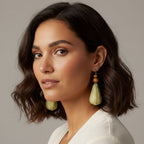 Woman wearing green earrings against a neutral background