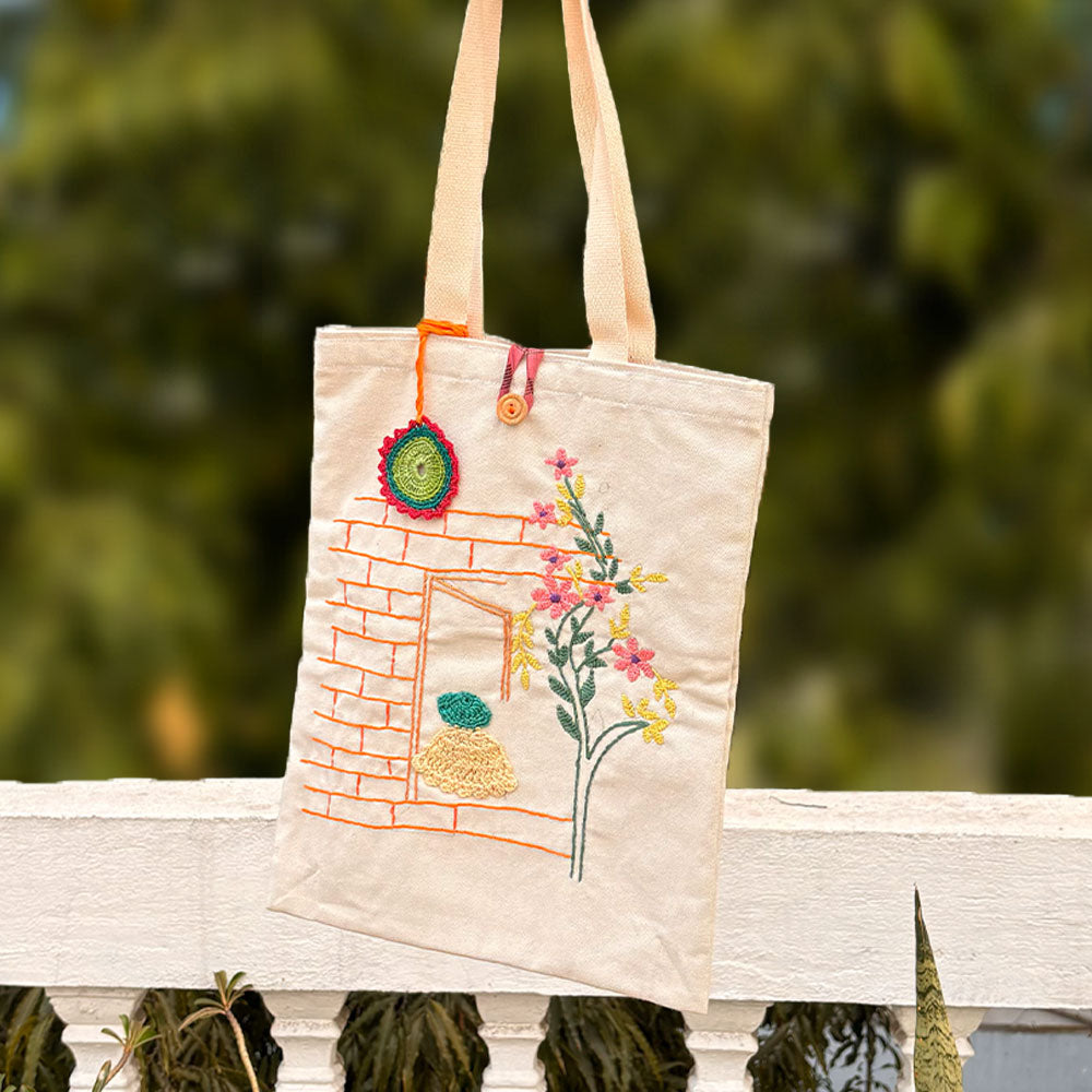 Tote bag with floral embroidery on a wooden bench with a blurred green background