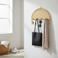 Woven wall hook with keys, sunglasses, and a black bag on a white wall.