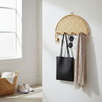 Woven wall hook with keys, sunglasses, and a black bag on a white wall.