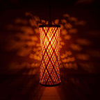 Decorative lamp with woven pattern casting shadows on a dark background