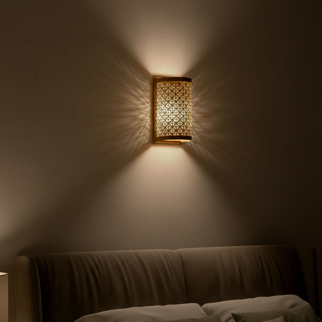 Decorative wall sconce casting a warm glow on a wall in a dimly lit room.