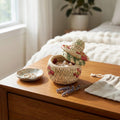 Woven jewelry box with floral patterns on a wooden surface with a soft, blurred background.