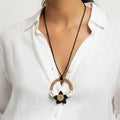 Necklace with a circular pendant worn by a person in a white shirt