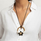 Necklace with a circular pendant worn by a person in a white shirt
