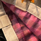 Close-up of beige canvas strap with pink and black plaid fabric lining