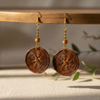 Pair of brown woven earrings on a wooden stand with a neutral background