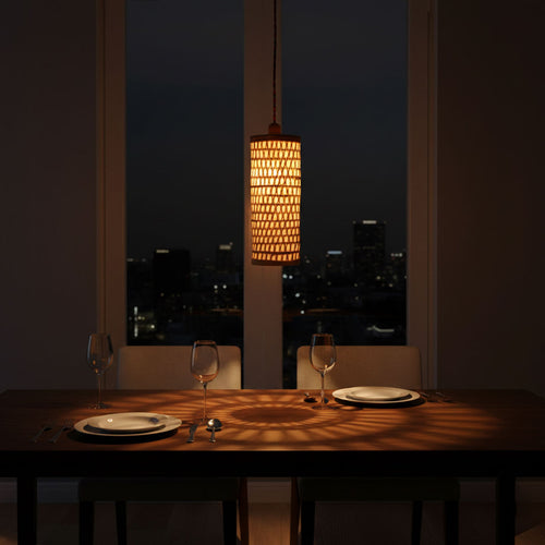 Dining table set for two with a lit lamp in the background, cityscape visible through window