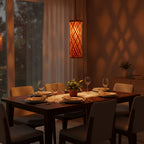 Dining table set for dinner with a warm ambiance, featuring a hanging lamp.