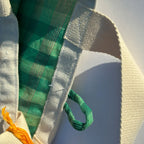 Close-up of a green and white woven bag with a plain background