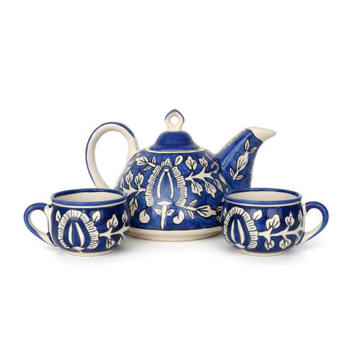 Blue and white ceramic teapot and two cups on a white background