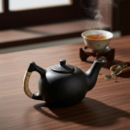 Black teapot on a wooden table with a cup of tea in the background