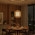 Dining room with a wooden table and chairs, illuminated by a pendant light.