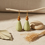 Green teardrop earrings with wooden beads on a natural background