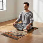 Man sitting in meditation on a colorful rug in a bright room