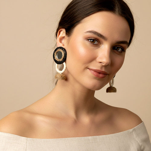 Woman wearing large hoop earrings against a beige background