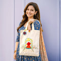Woman holding a tote bag with a colorful design against a light purple background