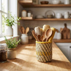 Kitchen counter with woven utensil holder and wooden spoons, shelves with kitchenware in the background.