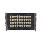 Black and beige diamond patterned rug with fringes on a white background